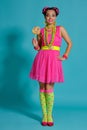 Lovely girl with a multi-colored braids hairstyle and bright make-up, posing in studio against a blue background