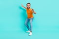 Full length photo of cheerful ecstatic man muscular beard wear orange t-shirt jeans surf on waterboard isolated on teal