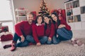 Full length photo of cheerful family sit floor spend time together xmas time decoration tree advent december indoors