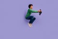 Full length photo of cheerful funny guy wear green pullover riding car jumping empty space isolated purple color