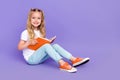 Full length photo of cheerful little girl tails sit read book do homework dressed stylish white blouse on