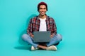 Full length photo of cheerful young man sitting floor use wireless netbook coworking isolated on teal color background Royalty Free Stock Photo