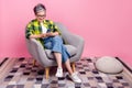 Full length photo of clever woman wear checkered shirt sit on armchair look at smartphone read post isolated on pink