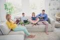 Full length photo of concentrated family sit couch mom dad two small kids girl boy read books in house indoors Royalty Free Stock Photo