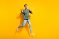 Full length photo of confident cheerful man dressed khaki t-shirt showing thumbs up jumping empty space isolated yellow