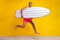 Full length photo of cool impressed shirtless man jumping high holding matrass isolated yellow color background