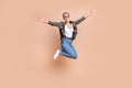 Full length photo of cool lucky woman wear khaki shirt rising fists jumping high emtpy space isolated beige color Royalty Free Stock Photo