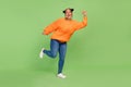 Full length photo of cool millennial brunette lady jump wear sweater jeans shoes isolated on green background