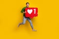 Full length photo of crazy young man brunet jump hold pinata notification red heart click like symbol isolated on yellow