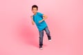 Full length photo of cute carefree small boy wear blue t-shirt dancing having fun isolated pink color background