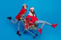 Full length photo of cute excited women santa elves wear ornament pullovers choosing x-mas gifts isolated blue color