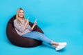 Full length photo of cute pretty girl dressed grey sweatshirt sitting bean bag pointing two fingers empty space isolated Royalty Free Stock Photo