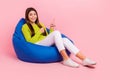 Full length photo of cute young girl sitting bean bag excited point empty space wear trendy green outfit isolated on Royalty Free Stock Photo