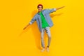 Full length photo of cute young male hands wings flying plane wear trendy jeans garment isolated on yellow color Royalty Free Stock Photo