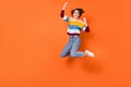 Full length photo of delighted girl fists up celebrate jumping high isolated on orange color background Royalty Free Stock Photo