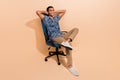 Full length photo of dreamy cheerful man wear print shirt sitting office armchair arms behind head isolated beige color Royalty Free Stock Photo