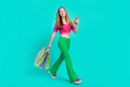 Full length photo of dreamy sweet schoolgirl wear pink crop top holding shoppers typing modern device isolated turquoise