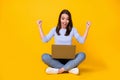 Full length photo of ecstatic girl sit floor legs crossed work remote laptop celebrate networking aim win raise fists Royalty Free Stock Photo