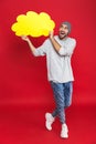 Full length photo of energetic man smiling and holding blank thought bubble isolated over red background Royalty Free Stock Photo