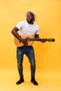 Full-length photo of excited artistic man playing his guitar in casual suite. Isolated on yellow background. Royalty Free Stock Photo