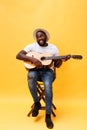 Full-length photo of excited artistic man playing his guitar. Isolated on yellow background. Royalty Free Stock Photo