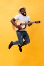 Full-length photo of excited artistic man playing his guitar. Isolated on yellow background. Royalty Free Stock Photo