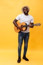 Full-length photo of excited artistic man playing his guitar. Isolated on yellow background. Royalty Free Stock Photo