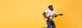 Full-length photo of excited artistic man playing his guitar.  on yellow background. Royalty Free Stock Photo