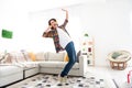Full length photo of excited cheerful guy dressed checkered shirt dancing listening music headphones indoors house home Royalty Free Stock Photo