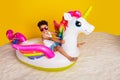 Full length photo of excited funky small boy wear white shirt swimming floating unicorn matrass isolated yellow color