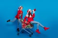 Full length photo of excited funky women santa elves wear ornament pullovers selling x-mas gifts isolated blue color