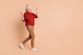 Full length photo of friendly funky lady dressed red pullover showing two v-signs walking empty space isolated beige