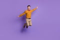 Full length photo of funky carefree young man wear plaid shirt bow tie jumping arms sides isolated violet color