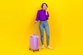 Full length photo of funky dreamy woman dressed purple shirt suitcase talking gadget looking empty space isolated yellow Royalty Free Stock Photo