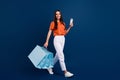 Full length photo of funky sweet woman dressed orange t-shirt holding shoppers virtual sale gadget isolated dark blue