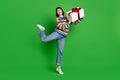 Full length photo of funny carefree young woman wear striped sweater smiling giving gift box isolated green color