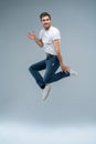 Full-length photo of funny man in casual t-shirt, blazer and jeans running or jumping in air isolated over gray Royalty Free Stock Photo