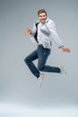 Full-length photo of funny man in casual t-shirt, blazer and jeans running or jumping in air isolated over gray Royalty Free Stock Photo