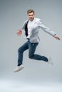 Full-length photo of funny man in casual t-shirt, blazer and jeans running or jumping in air isolated over gray