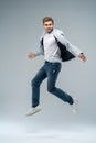 Full-length photo of funny man in casual t-shirt, blazer and jeans running or jumping in air isolated over gray Royalty Free Stock Photo