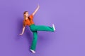 Full length photo of glad joyful sweet girl wear trendy clothes have fun raise leg look empty space isolated on purple