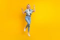 Full length photo of good mood adorable girl dressed print shirt jumping showing v-sign symbol isolated on yellow color Royalty Free Stock Photo