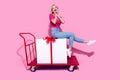 Full length photo of good mood lovely cute woman riding on shopping cart with large present palms on cheeks isolated on