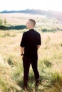 Full length photo of handsome young man in black shirt and pants, standing outdoor in the beautiful green summer field Royalty Free Stock Photo