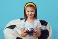 Girl sitting on bean bag chair, holding joystick and playing video games Royalty Free Stock Photo