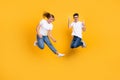 Full length photo of harsh cool young couple wear white t-shirt jumping showing hard rock sign guitarist isolated yellow Royalty Free Stock Photo