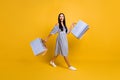 Full length photo of impressed funny young lady wear striped dress holding bargains walking isolated yellow color Royalty Free Stock Photo