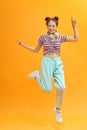 Full length photo of joyful lady jumping high listening modern youngster playlist music through cool earflaps isolated on yellow Royalty Free Stock Photo