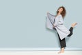 Full-length photo of a joyful woman in a blue cardigan jumping on a blue background.