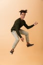 Full length photo of joyous african american guy wearing sweater laughing and jumping, isolated over beige background